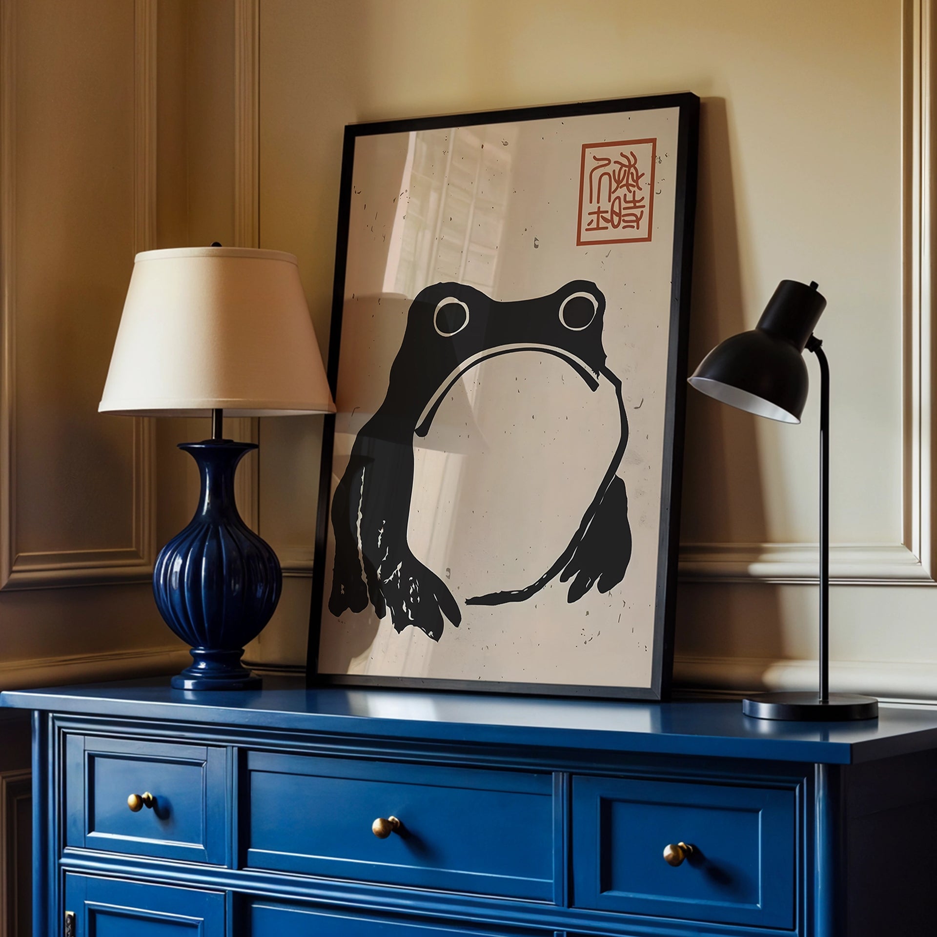Framed artwork of a black frog on a blue dresser with two lamps.